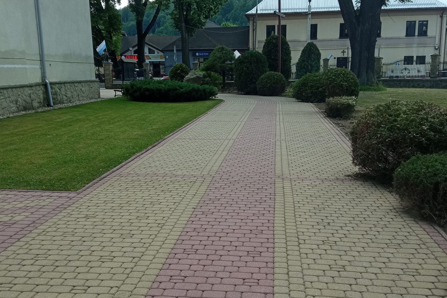 Umyta alejka z kostki brukowej prowadząca przez park